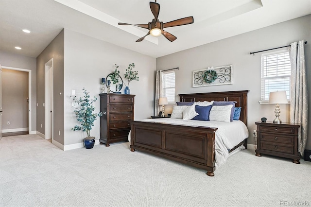 bedroom featuring light colored carpet, ceiling fan, and a tray ceiling