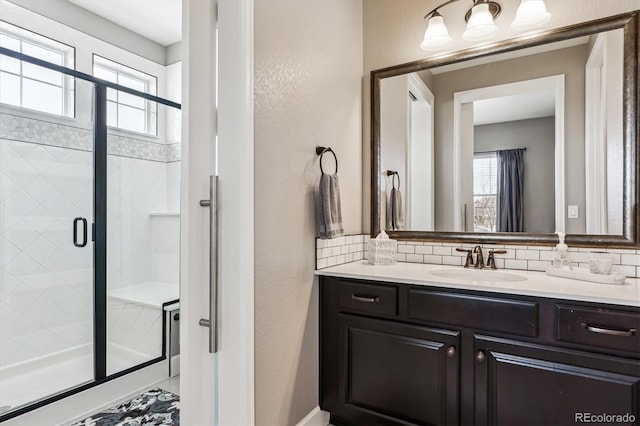 bathroom with vanity, a shower with door, and decorative backsplash