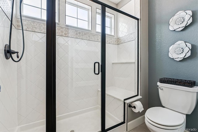 bathroom featuring plenty of natural light, a shower with door, and toilet