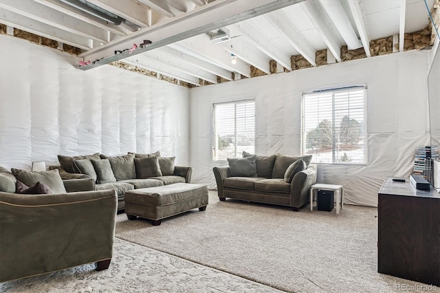 carpeted living room featuring beamed ceiling