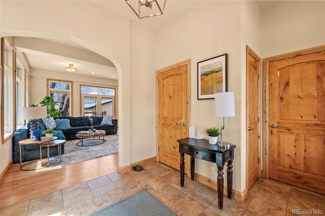 entryway with arched walkways, a high ceiling, and baseboards