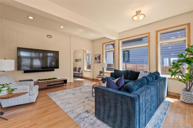 living area featuring recessed lighting, arched walkways, light wood-type flooring, and baseboards