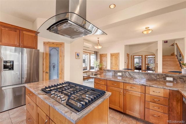 kitchen with light stone countertops, brown cabinets, island exhaust hood, and appliances with stainless steel finishes