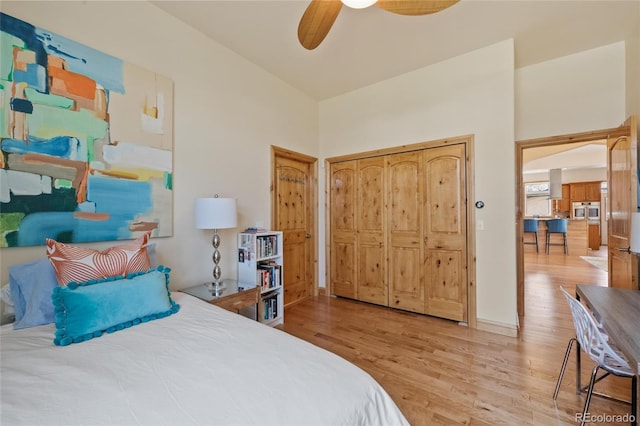 bedroom with light wood-style flooring, a towering ceiling, and a ceiling fan