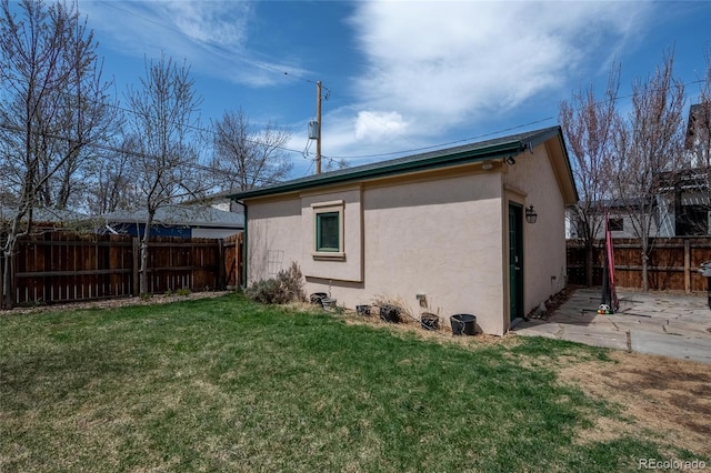 rear view of house with a patio, stucco siding, a fenced backyard, and a lawn
