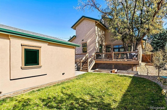 rear view of house featuring a yard, fence, a wooden deck, and stucco siding