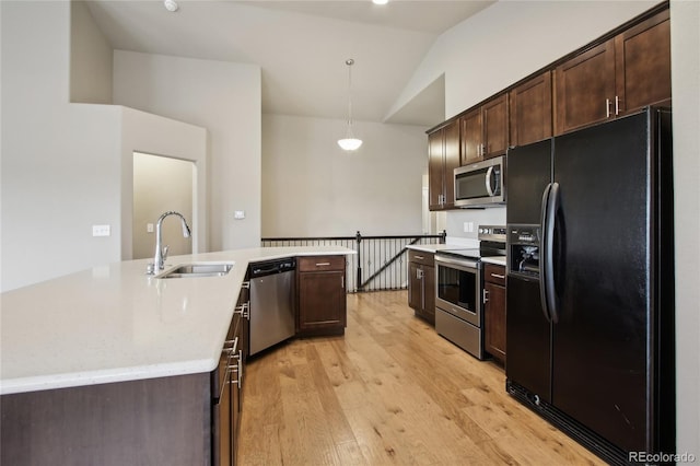 kitchen with dark brown cabinetry, a sink, light wood-style flooring, vaulted ceiling, and stainless steel appliances