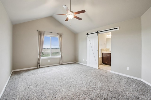 unfurnished bedroom featuring baseboards, light carpet, a barn door, and lofted ceiling