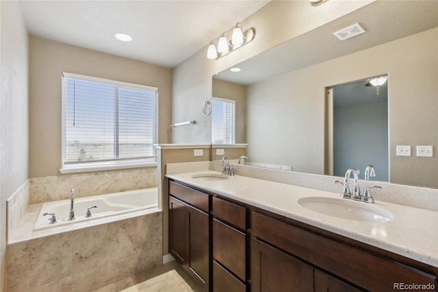 full bathroom with double vanity, visible vents, a sink, and a garden tub