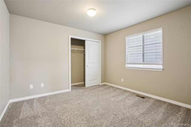 unfurnished bedroom featuring carpet flooring, baseboards, visible vents, and a closet