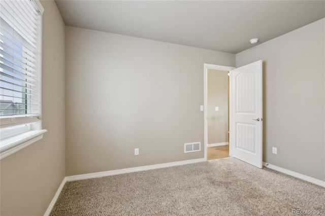 empty room with visible vents, baseboards, and carpet floors