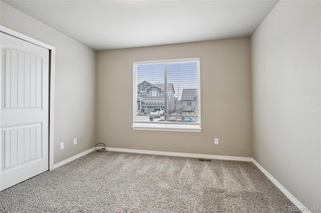 spare room featuring carpet flooring, baseboards, and visible vents
