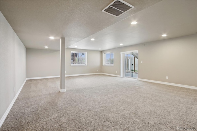 basement with baseboards, light colored carpet, recessed lighting, and visible vents