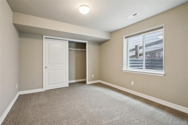 unfurnished bedroom with visible vents, baseboards, carpet floors, and a closet