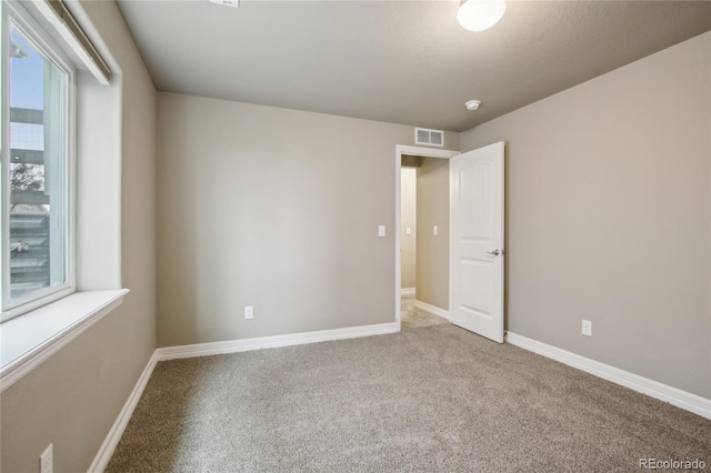 unfurnished room featuring baseboards, carpet, and visible vents
