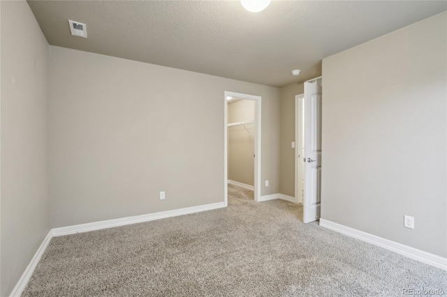empty room with baseboards, visible vents, and light carpet