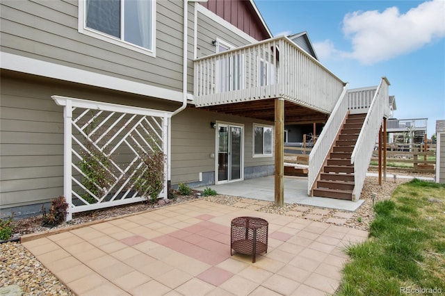 rear view of house with stairs, board and batten siding, a deck, and a patio