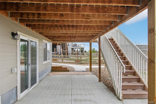 view of patio featuring fence and stairway