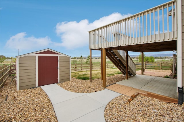 view of patio featuring a shed, an outbuilding, stairway, and fence