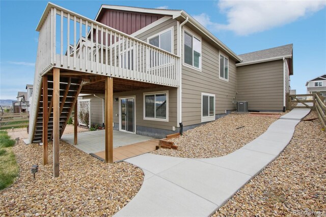 back of house with a wooden deck, a patio, board and batten siding, central air condition unit, and stairway