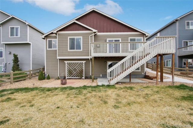 rear view of house featuring a lawn, a deck, fence, and stairs