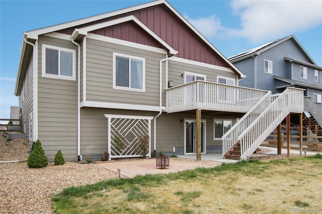 rear view of property featuring stairs, a wooden deck, board and batten siding, a patio, and a yard