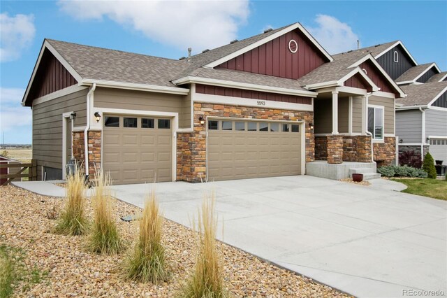 craftsman house with a shingled roof, an attached garage, stone siding, board and batten siding, and concrete driveway