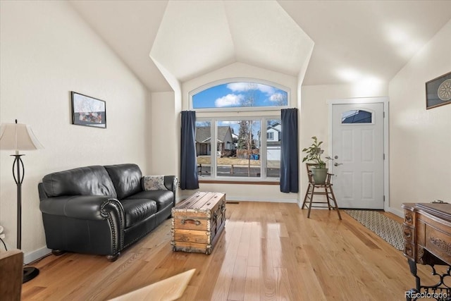 interior space with light wood-type flooring, lofted ceiling, and baseboards