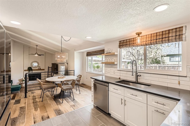 kitchen featuring decorative backsplash, dark countertops, dishwasher, a sink, and white cabinets