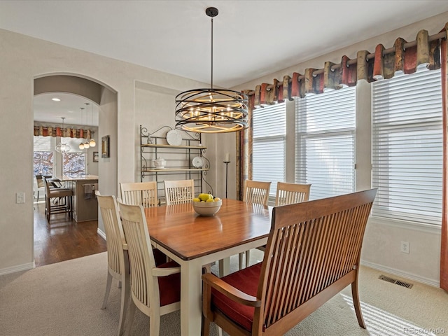 carpeted dining area with an inviting chandelier