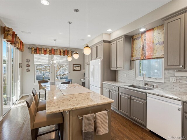 kitchen with white appliances, a center island, sink, and hanging light fixtures