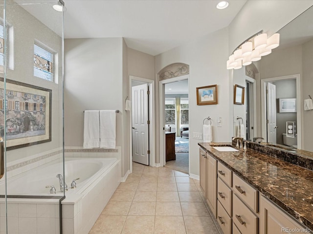 bathroom with vanity, tile patterned flooring, and tiled bath