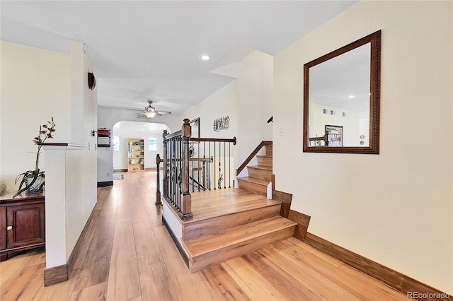 stairway with wood-type flooring and ceiling fan