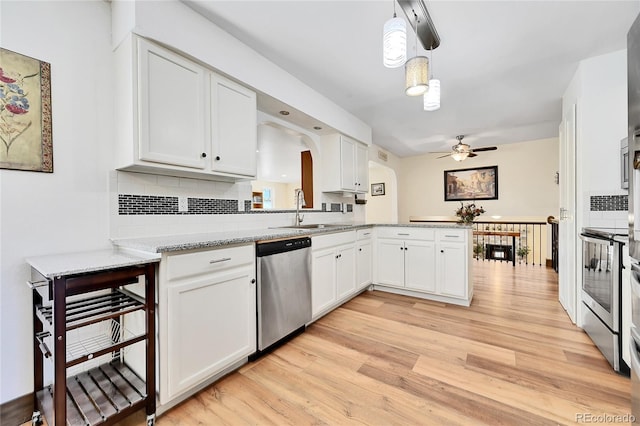 kitchen featuring appliances with stainless steel finishes, pendant lighting, white cabinetry, sink, and kitchen peninsula