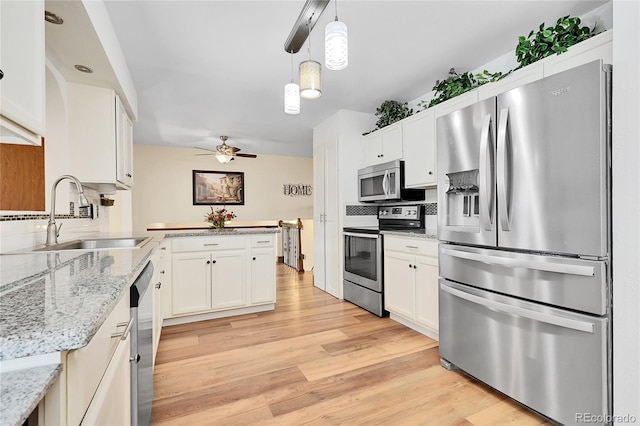 kitchen featuring sink, appliances with stainless steel finishes, hanging light fixtures, light stone countertops, and white cabinets