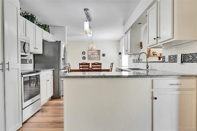 kitchen with hanging light fixtures, white cabinetry, and appliances with stainless steel finishes