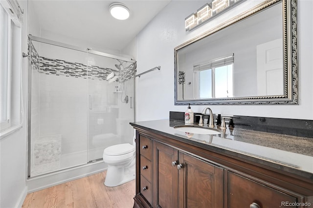 bathroom with hardwood / wood-style flooring, vanity, a shower with door, and toilet