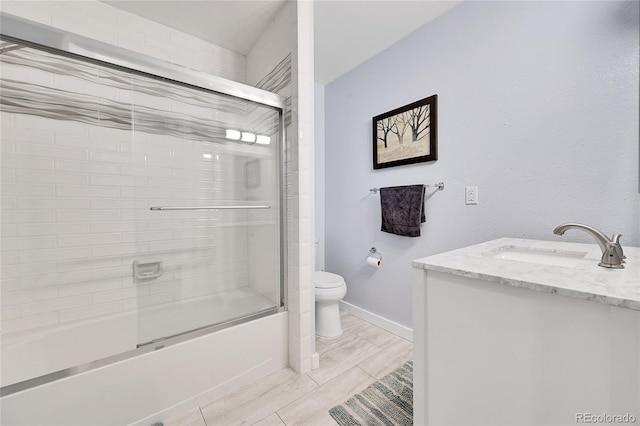 full bathroom with toilet, vanity, and bath / shower combo with glass door