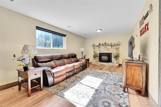 living room featuring a stone fireplace and light hardwood / wood-style flooring