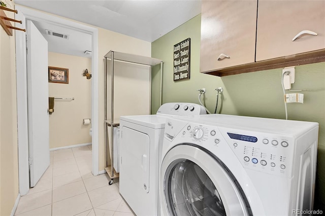 clothes washing area with cabinets, light tile patterned floors, and independent washer and dryer