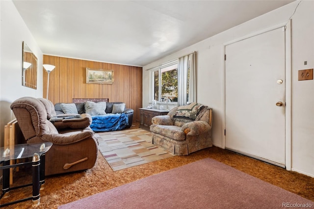 carpeted living room featuring wood walls