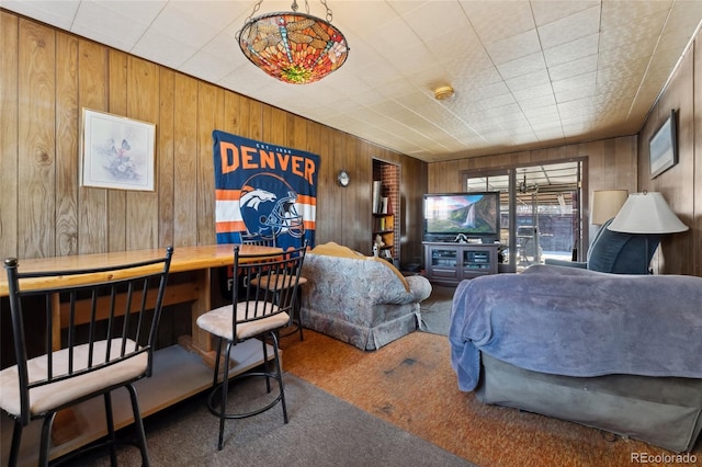 carpeted bedroom featuring wooden walls