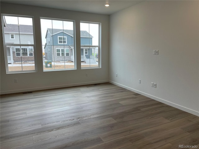 unfurnished room with recessed lighting, wood finished floors, visible vents, and baseboards