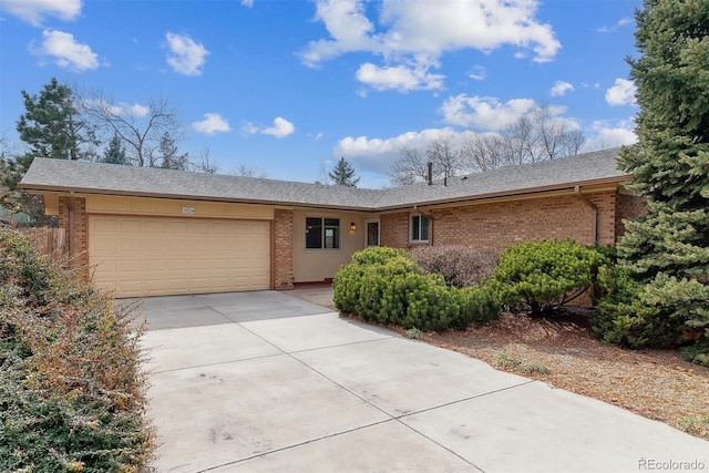 single story home with concrete driveway, brick siding, and a garage