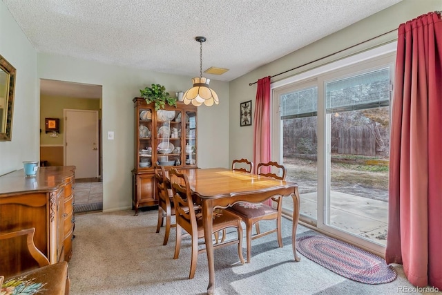 dining space featuring visible vents, light colored carpet, and a textured ceiling