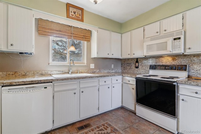 kitchen featuring visible vents, backsplash, light countertops, white appliances, and a sink