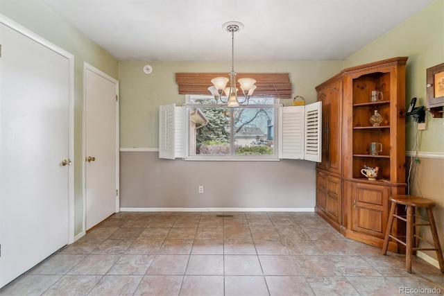 unfurnished dining area with light tile patterned flooring, baseboards, and an inviting chandelier