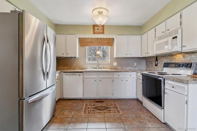 kitchen with visible vents, backsplash, light countertops, white appliances, and a sink