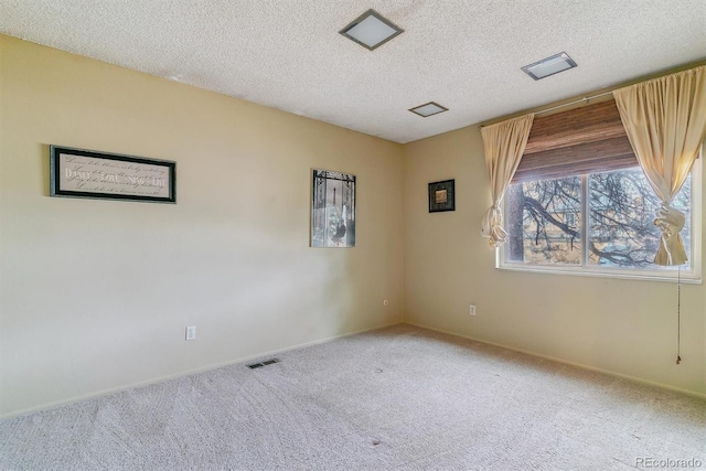 carpeted empty room featuring baseboards, visible vents, and a textured ceiling