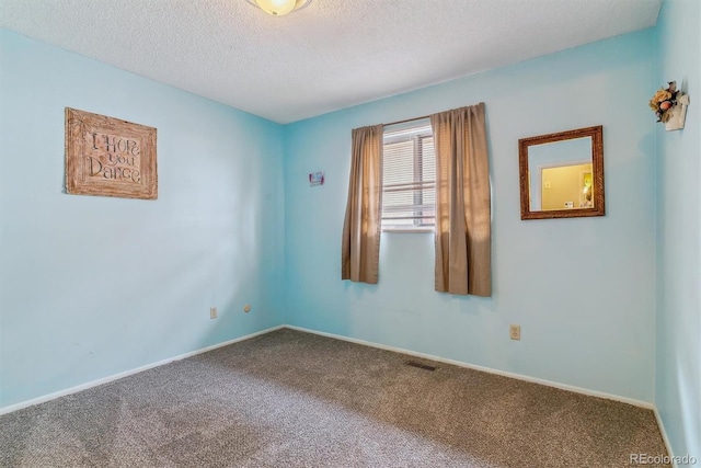 carpeted spare room featuring visible vents, baseboards, and a textured ceiling